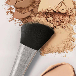 Close up of Mirabella's Foundation Contour Vegan Brush atop a powder swatch of Invincible For Pure Press powder on a white background.