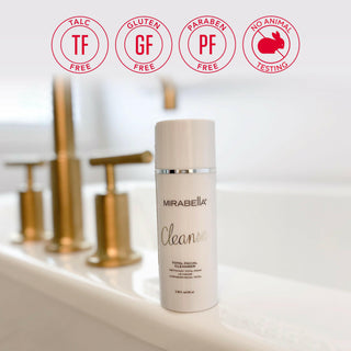 Total Facial Cleanser by Mirabella shown by a sink with gold fixtures and the brand's core value emblems floating above the image.